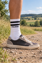 PFALZKIND Tennissocke mit schwarzen Streifen, getragen mit Sneaker auf einem Feldweg